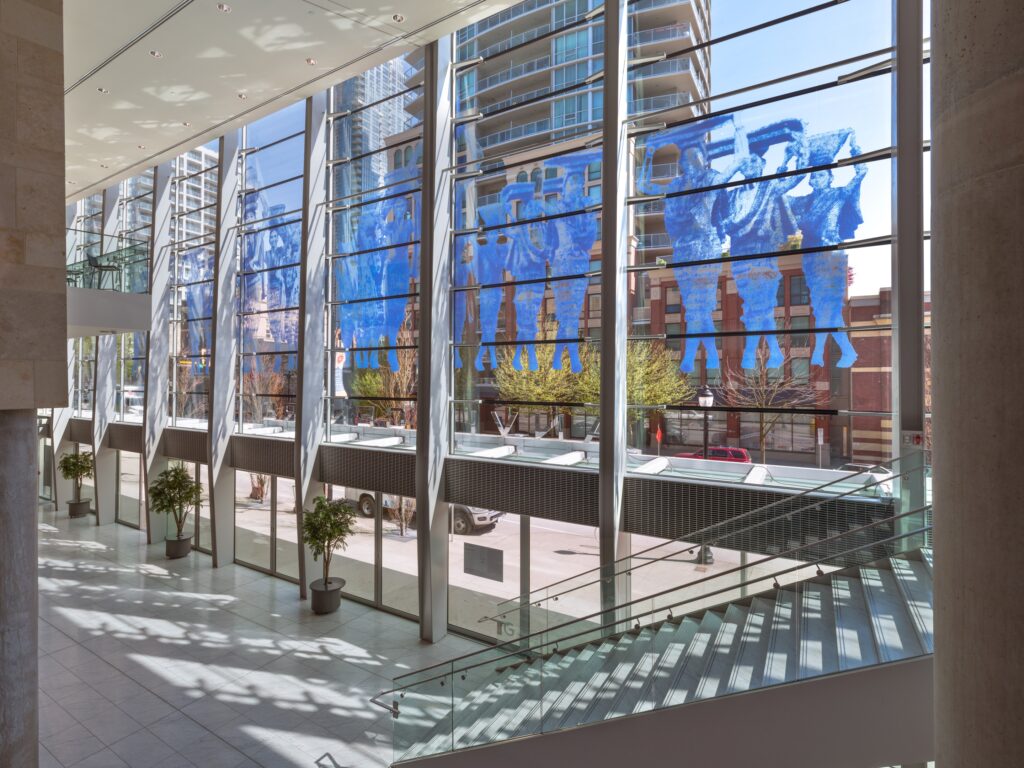 A window wrap in monochrome blue fills the upper floors of the Anvil Centre with images of people walking and carrying various objects on their heads